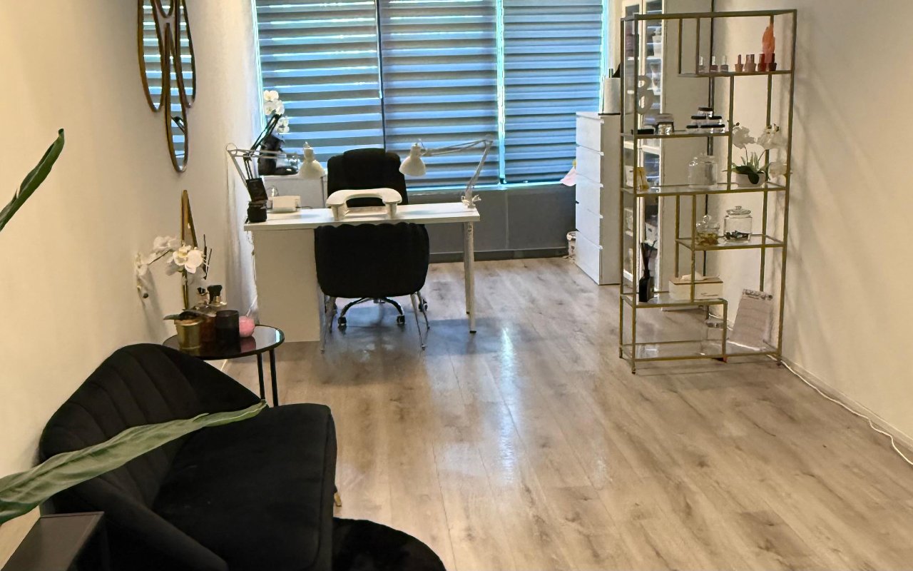 De studio met een plant, gouden rekken en de behandelplek bij het raam